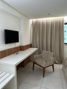 ein Zimmer mit Schreibtisch, Fernseher und Stuhl in der Unterkunft Flat em Palmas no Vivence hotel in Palmas + 2 Fotos