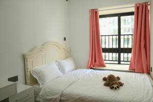 a teddy bear laying on a bed with a window at Miri apartment in Kunming