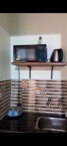 a microwave sitting on a shelf above a sink at Monica guest house in Varca
