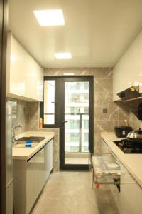 a kitchen with white counters and a door with a window at Miri apartment in Kunming +12 photos