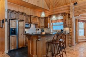 a kitchen with wooden cabinets and a bar with stools at Fiddler Lake Resort - Deer 80 in Mille-Isles +22 photos