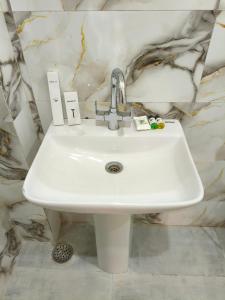 a white sink in a bathroom with a marble wall at BODHI Residency in Greater Noida