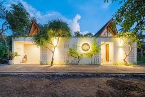 a house with two palm trees in front of it at Tropicool Hideaway Villas in Nusa Lembongan