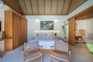 a bedroom with a bed and two chairs at Tropicool Hideaway Villas in Nusa Lembongan