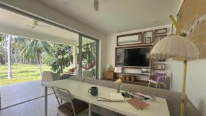 a living room with a couch and a table and a tv at Villa Colette in Ban Hua Laem Ma So