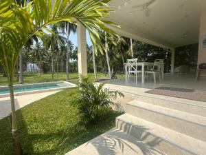 a house with a patio with a table and palm trees at Villa Colette in Ban Hua Laem Ma So