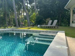 a swimming pool with two chairs and a bench in a yard at Villa Colette in Ban Hua Laem Ma So