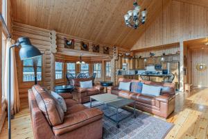 a living room with leather furniture in a log cabin at Fiddler Lake Resort - Deer 41 in Mille-Isles