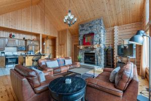 a living room with leather furniture and a stone fireplace at Fiddler Lake Resort - Deer 41 in Mille-Isles
