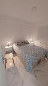 a bed in a white room with two lights on at Arena Studio Mar de Ajó in Mar de Ajó