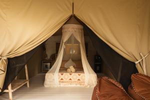 a bed with a teddy bear in a tent at Exotic private glamping in Nusa Penida