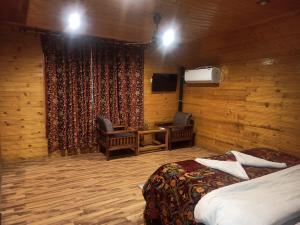 a hotel room with two beds and a desk and a television at Birdsong pahalgam in Pahalgām