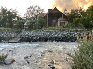 a house with a stone wall next to a river at Birdsong pahalgam in Pahalgām