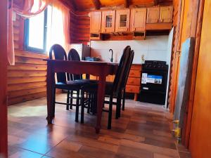 a kitchen with a wooden table with chairs and a stove at Cabañas Paraje de los Sueños in Uspallata