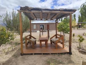 a wooden gazebo with two chairs and a table at Cabañas Paraje de los Sueños in Uspallata