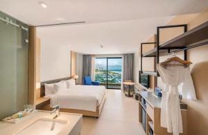 a large hotel room with a bed and a sink at ARENA JKV condotel in Nha Trang