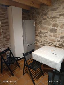 a room with a table and two chairs and a refrigerator at "la Casita" in Boiro