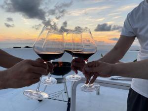 three people holding wine glasses with the sunset in the background at 天海の城 in Saikai