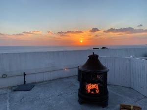 a fireplace on a balcony with the sunset in the background at 天海の城 in Saikai