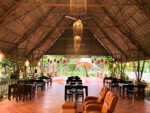 a restaurant with tables and chairs and a large ceiling at An Tiên Ecolodge in Tân Phú