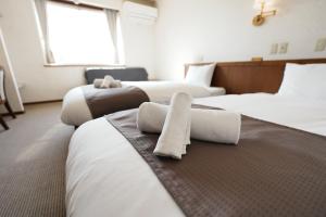 a hotel room with three beds with towels on them at Hostel SAMURISE NORTH in Fujikawaguchiko