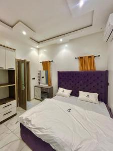 a bedroom with a large bed with a purple headboard at City Xcape Niche in Lekki
