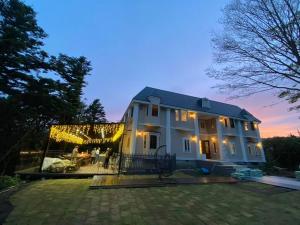 a white house with people standing outside of it at Izu Plateau House 420 square meters, BBQ , 8 bedrooms, 1 living room 1kitchen 6 toilets 4 bathroom 1 onsen in Yawatano