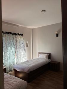 a bedroom with two beds and a window at Yatra Chhen in Bhaktapur