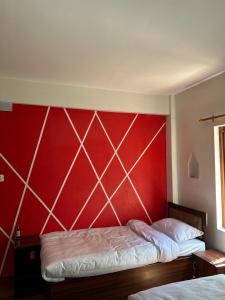 two beds in a room with a red wall at Yatra Chhen in Bhaktapur +4 photos