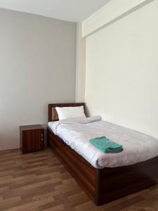 a bedroom with a bed with white sheets and wooden floors at Yatra Chhen in Bhaktapur