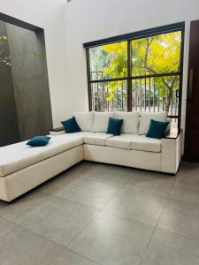 a white couch in a room with a large window at Mack Win Villa in Pannipitiya