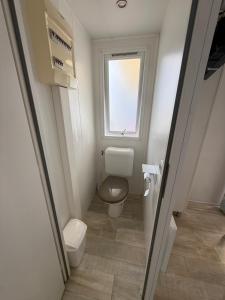 a small bathroom with a toilet and a window at Chez Angel et Flo - E27 - Mobil home tout confort - 15 minute Europa Park - terrasse privée in Boofzheim +14 photos