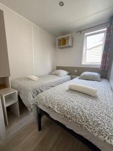 a bedroom with two beds and a window at Chez Angel et Flo - E27 - Mobil home tout confort - 15 minute Europa Park - terrasse privée in Boofzheim