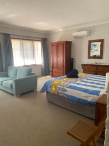 a bedroom with a bed and a couch and a chair at Bentworth Lodge in Carramar