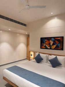a bedroom with a large bed with a painting on the wall at Kolas Grand - Hotel and Convention Center in Warangal