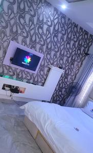a bedroom with a bed and a tv on a wall at City Xcape Niche in Lekki