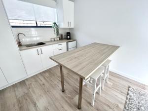 a kitchen with a wooden table and white cabinets at Private Barwon Heads Cottage Walk to River in Barwon Heads