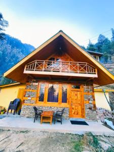 a house with a balcony and a table in front of it at Lambri View Treehouse Jibhi in Jibhi