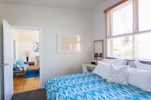 um quarto com uma cama com lençóis azuis e brancos em Sunset Over Sea Little Beachside Villa Rosebud McCrae em Rosebud