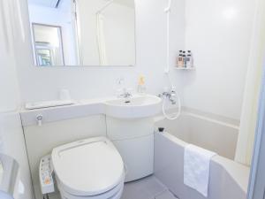 a white bathroom with a toilet and a sink at Hotel Cuore Nagasaki Ekimae in Nagasaki