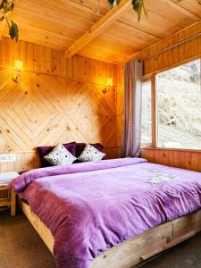 a bedroom with a large bed with a wooden wall at Lambri View Treehouse Jibhi in Jibhi