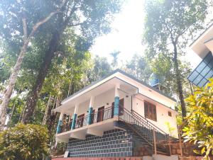 a house with a balcony in the middle of trees at Green Leaf in Padinjarathara