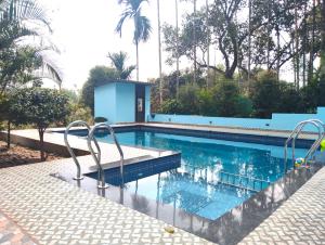 a swimming pool with two chairs next to it at Green Leaf in Padinjarathara