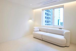 a white couch in a room with a window at Canvas Hostel in Busan