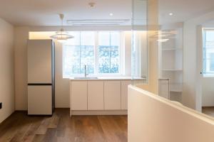 a kitchen with white cabinets and a window at Canvas Hostel in Busan
