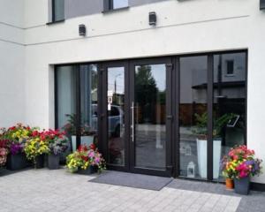 a glass door of a building with potted flowers at Hotel Amber in Raszyn