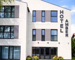 a white building with black windows at Hotel Amber in Raszyn