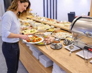 a woman standing in front of a buffet with food at Hotel Amber in Raszyn