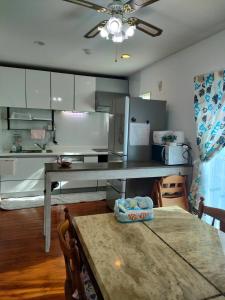 a kitchen with a table and a ceiling fan at ほぬのいえ Honu's house in Uruma