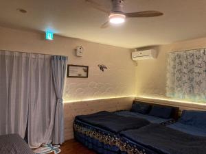 a bedroom with two beds and a ceiling fan at ほぬのいえ Honu's house in Uruma